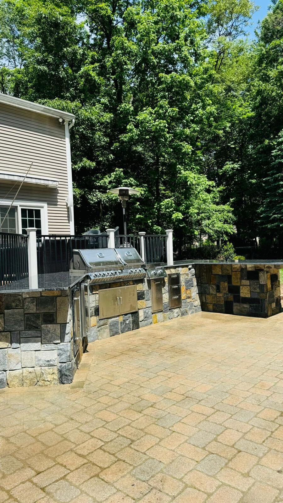 Stone veneer outdoor kitchen island with granite countertop and built-in grills
